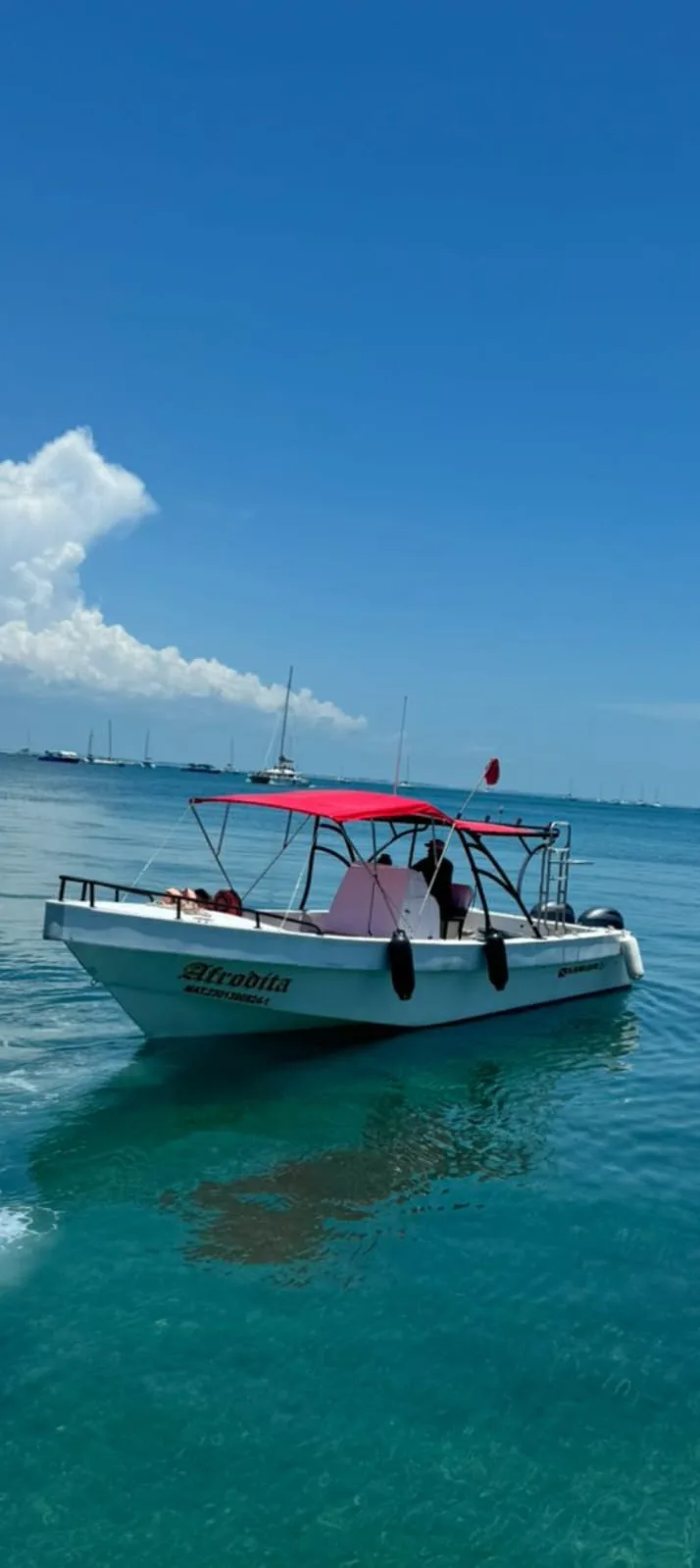 Lancha con toldo rojo navegando frente a Isla Mujeres