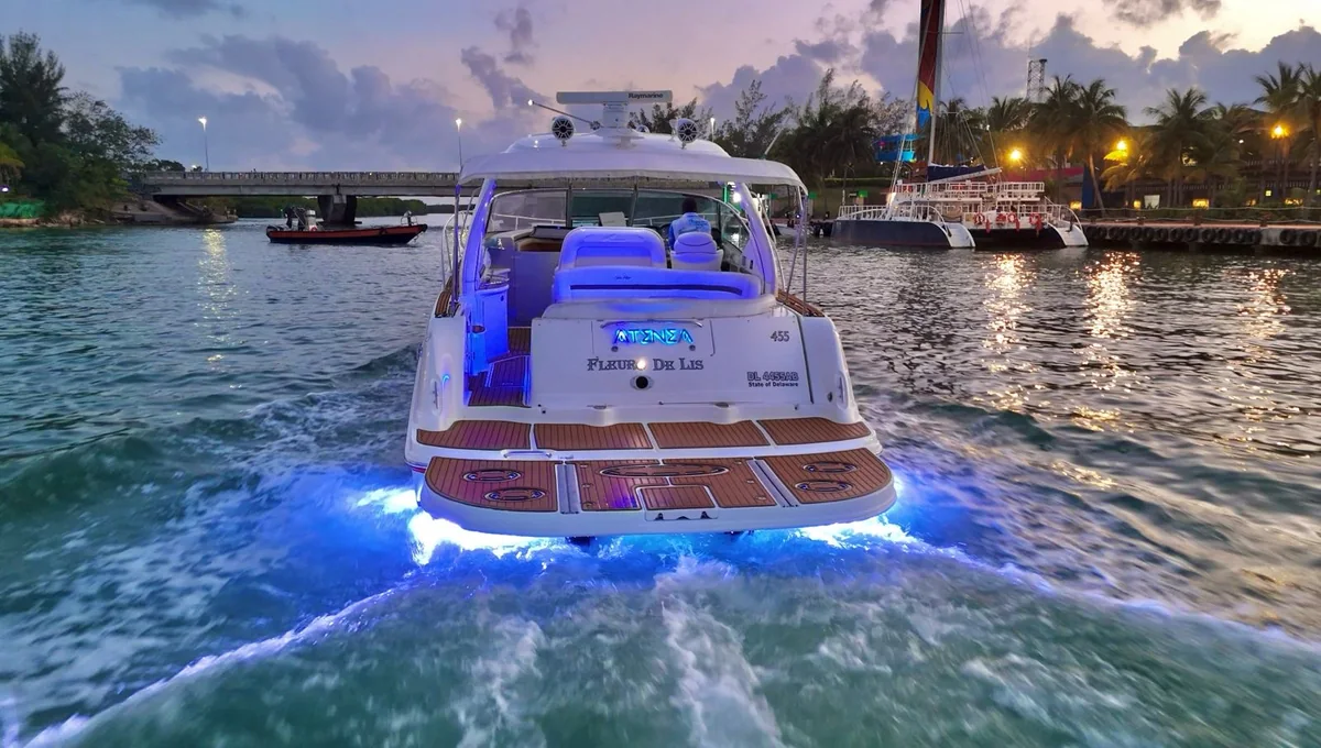 Yate con luces azules navegando al anochecer en Isla Mujeres